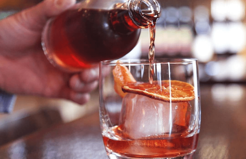 pouring Negroni from glass bottle