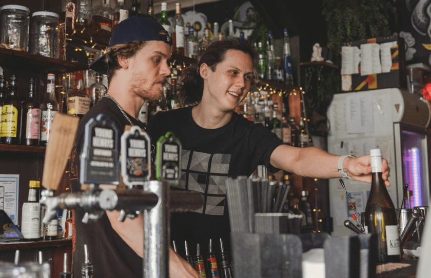 Two men at the bar serving customers