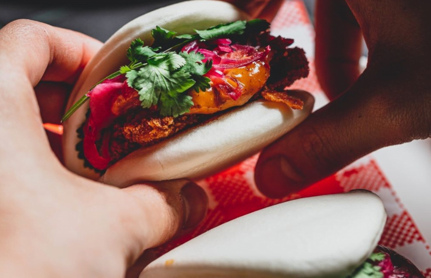 Hand holding pork bao bun at Ni Ho Bar.
