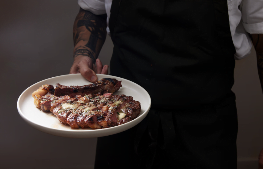 Chef presenting Folly's ribeye steak at new restaurant Folly's Bar & Bistro.