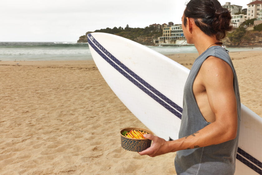 Man with DOPA and surfboard on Bondi Beach.