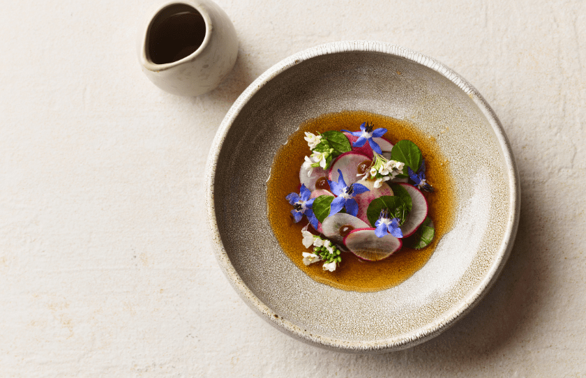 Tasting menu dish - colourful food on a round plate in a jus - Aria 25th Birthday