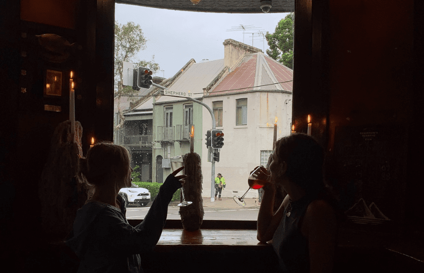 Two ladies sitting next to the widow, enjoying their drinks and looking outside