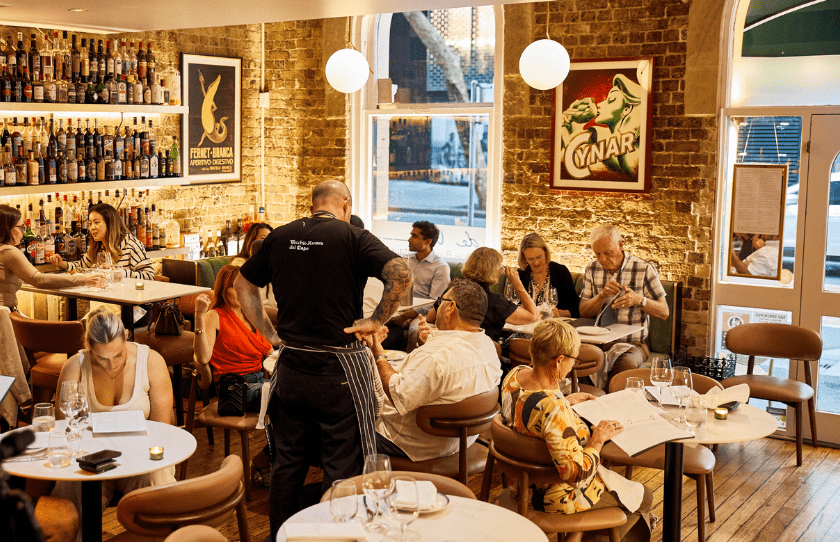 de Vine venue while a busy service, with people sitting and waiters taking order and Amaro collection at the back - Best European Venues in Sydney