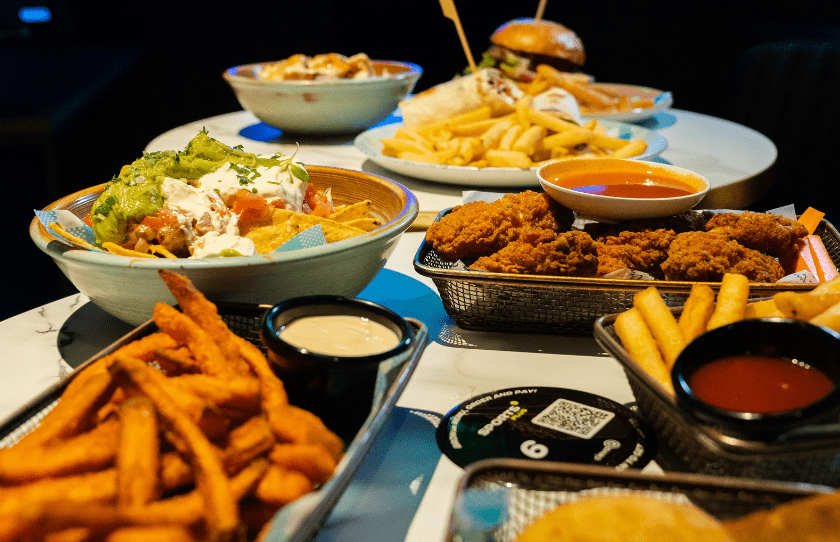 Sports Plus Immersive Experience - food offerings, pub grub on a table including burgers nachos and fries