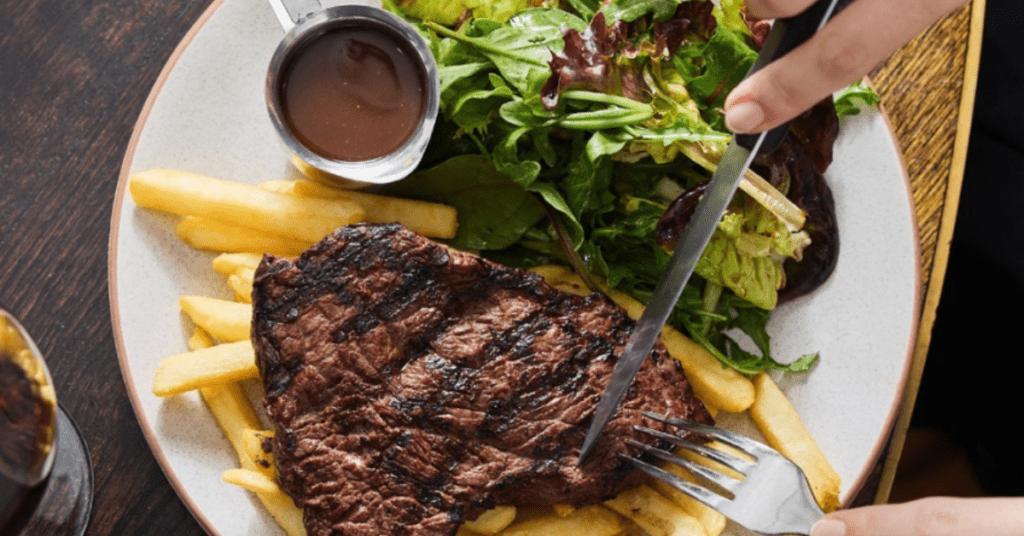 A picture of the steak with fries, salad, chips and sauce