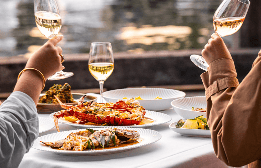 Sydney Restaurant Group 50% Off Set Menu - Manta. Food on the table and wine. Lobster on a white plate and people with wine glasses in hand