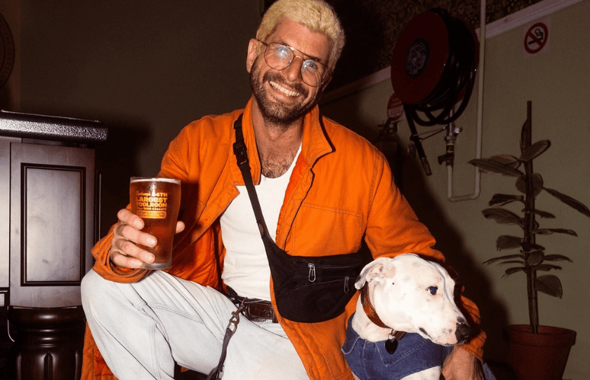 man with his dog holding a pint in the new bat and ball